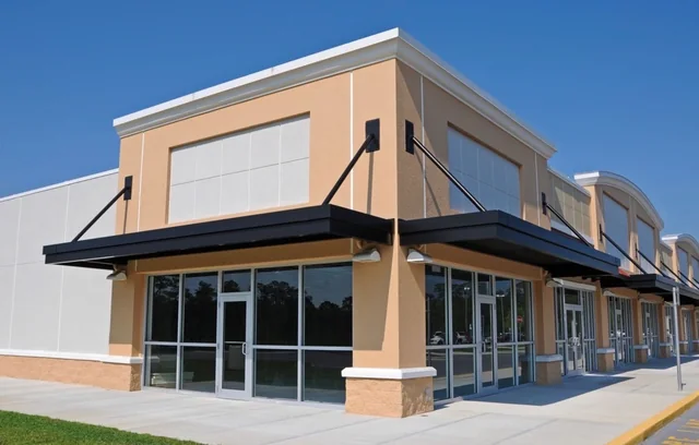 Commercial storefront exterior with tan walls, white trim and black awnings