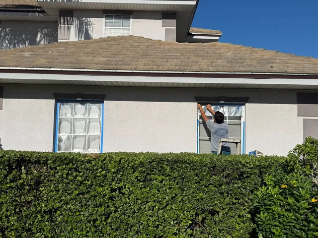 Painter masking a house window in preparation for exterior painting